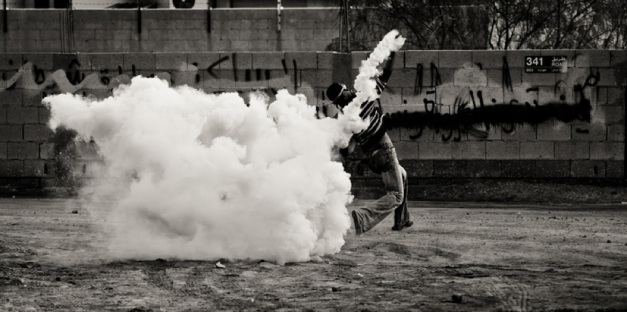 Διαδηλωτής πετάει δακρυγόνο πίσω στην αστυνομία στην Σίτρα, τον Δεκέμβριο 2011 (φωτο Saeed Saif)